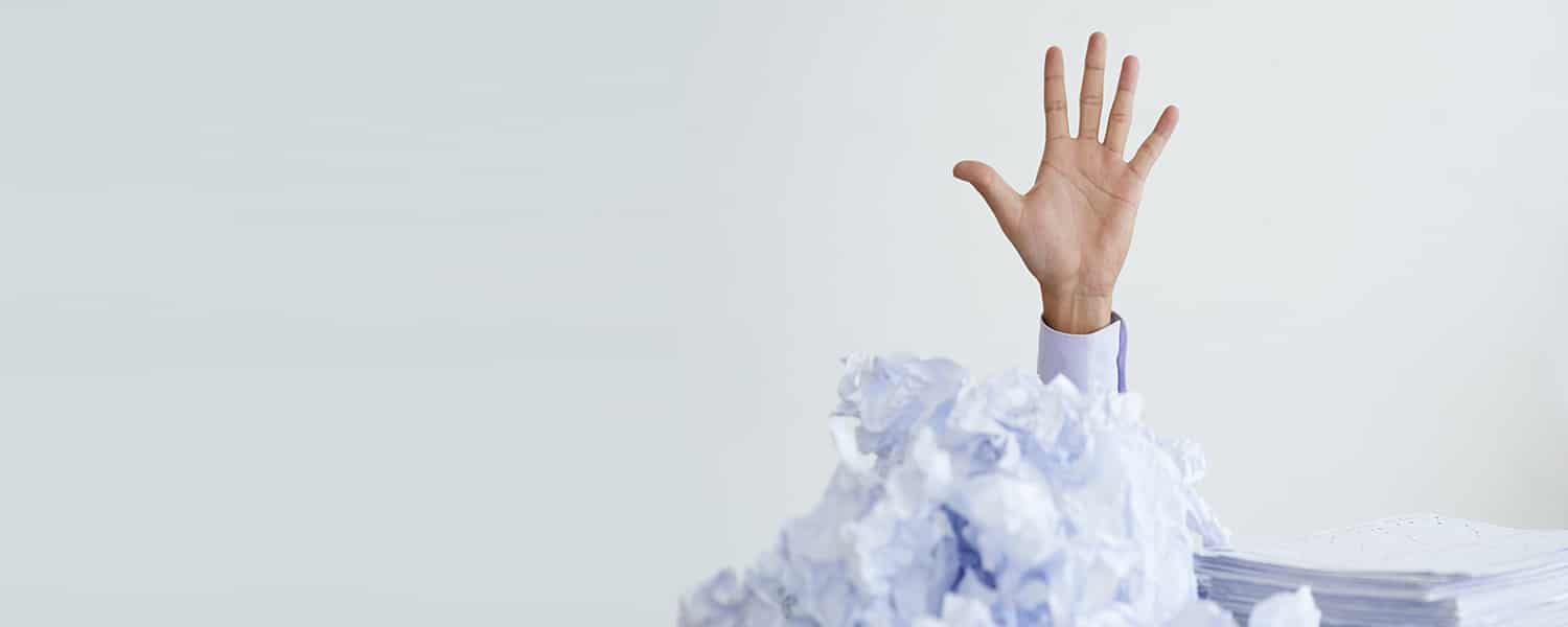 When to Outsource Marketing | Outsourcing Your Marketing | Hand Emerges from Stack of Papers
