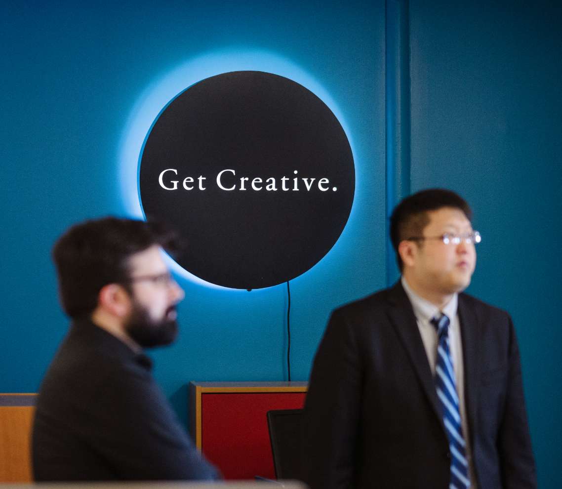 Get creative sign with two DOM team members blurred in the foreground